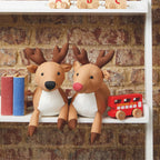 Two plush deer toys on a shelf with a brick wall background