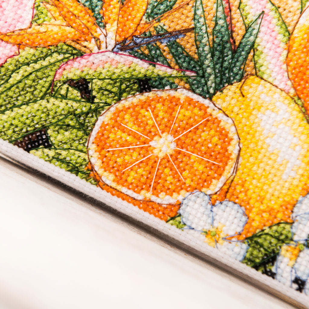 Close-up of a cross-stitched piece with fruits and leaves