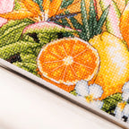 Close-up of a cross-stitched piece with fruits and leaves