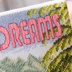 Cross-stitched patch with 'Dreams' text and nature design