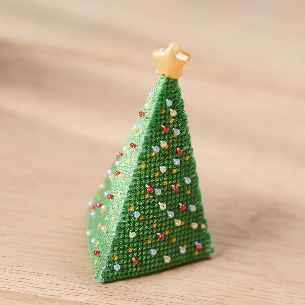 Knitted Christmas tree ornament with a star on top against a beige background