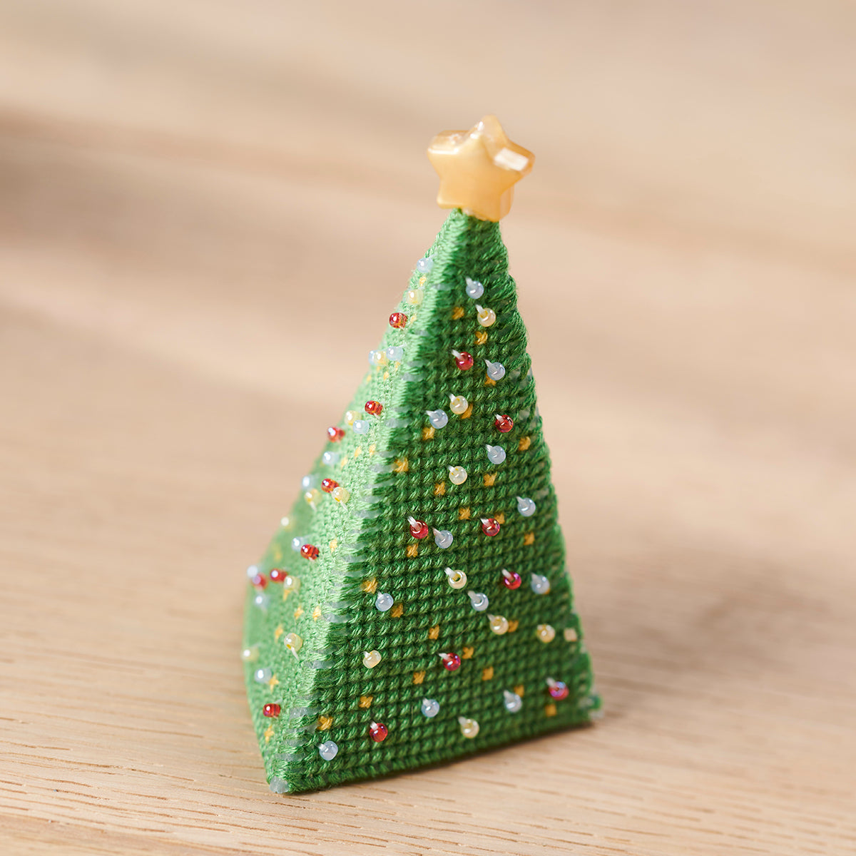 Knitted Christmas tree ornament with a star on top against a beige background