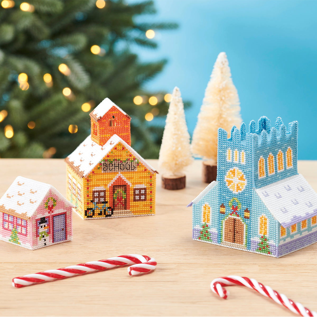 Decorative Christmas village scene with miniature houses and candy canes on a wooden surface.