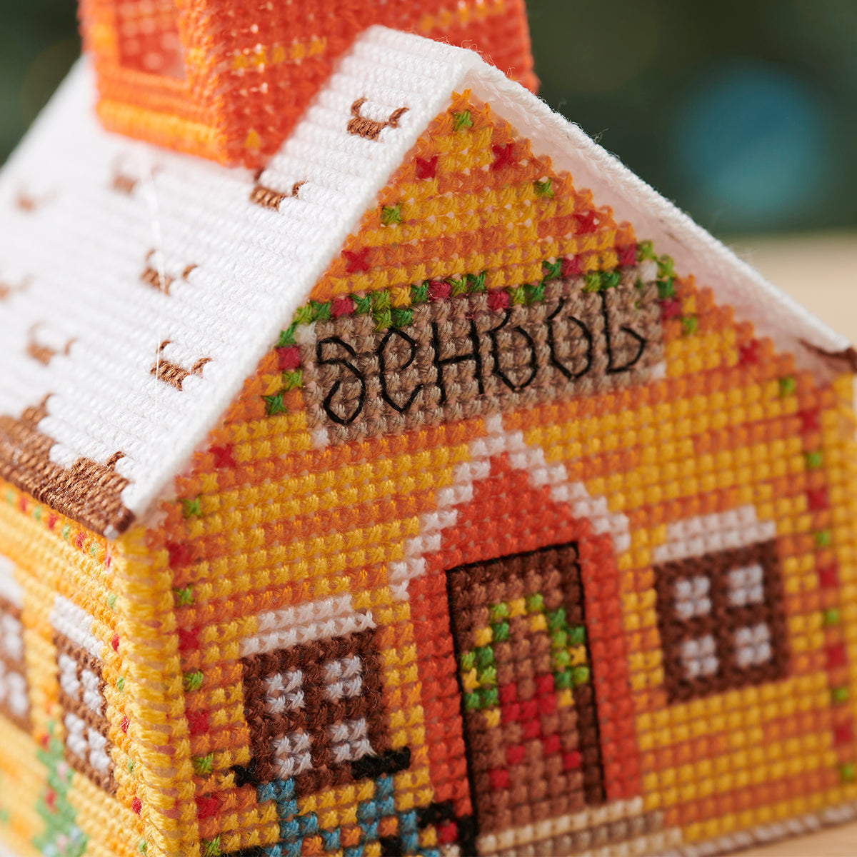 Cross-stitched model of a school building with colorful details.