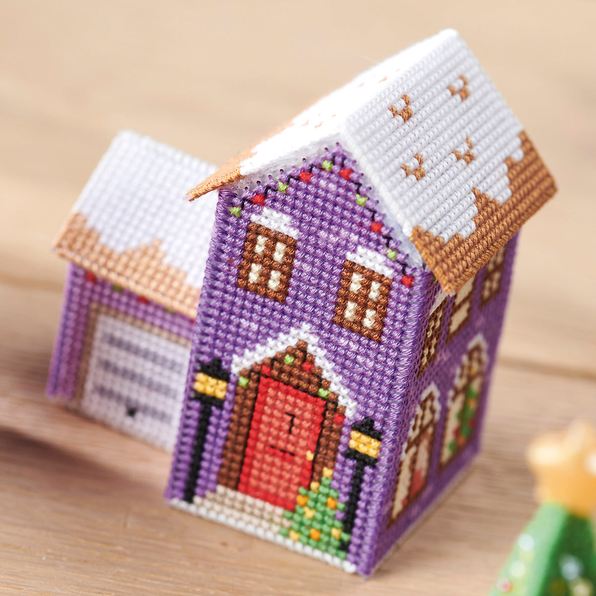 Cross-stitched miniature house on a wooden surface