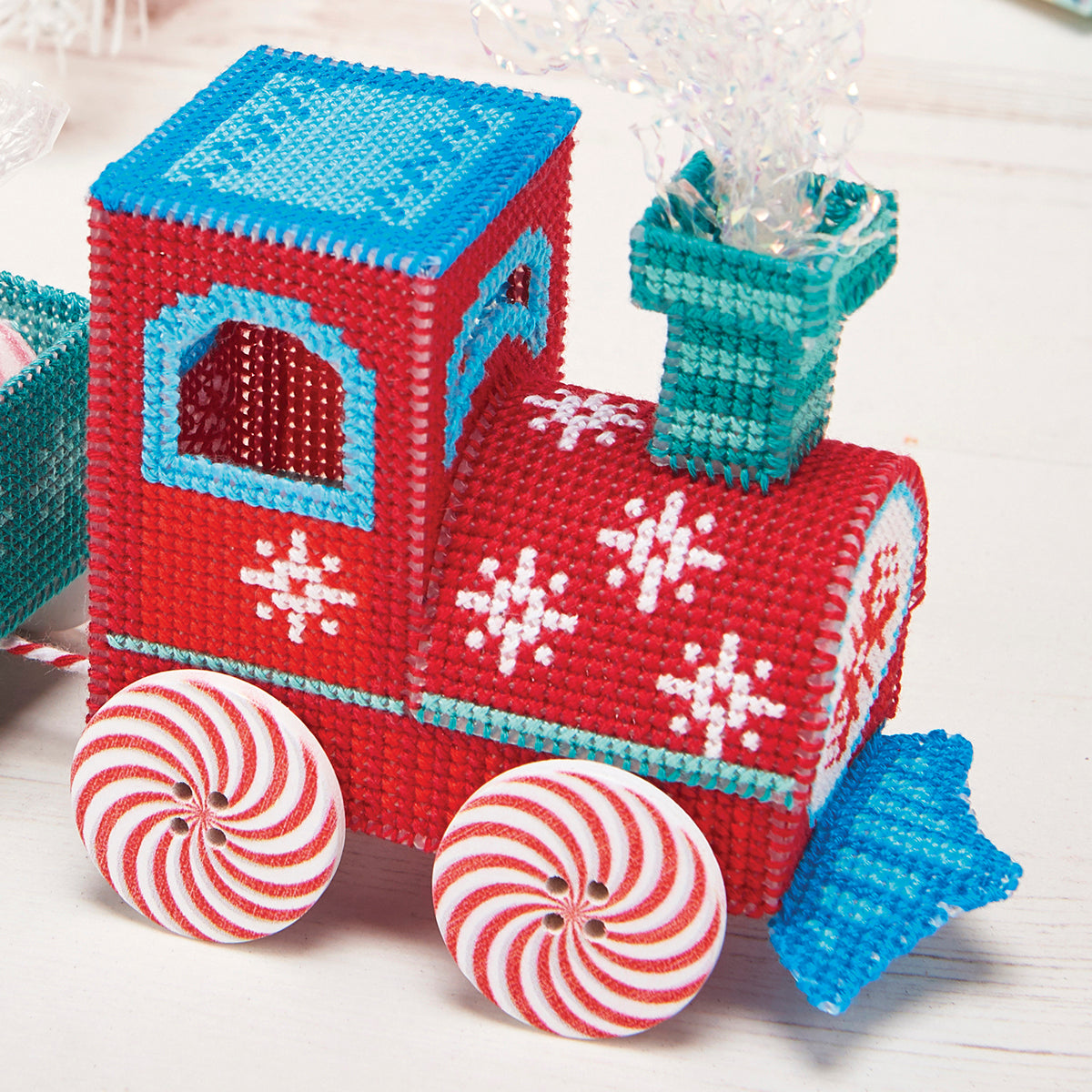 Red toy train with blue roof and peppermint candy wheels on a white background