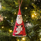 Red Santa Claus ornament hanging on a Christmas tree with lights.