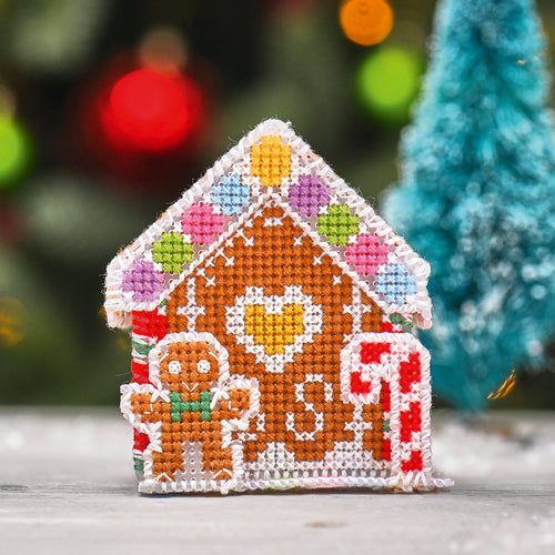 Cross-stitched gingerbread house with a blurred Christmas tree in the background