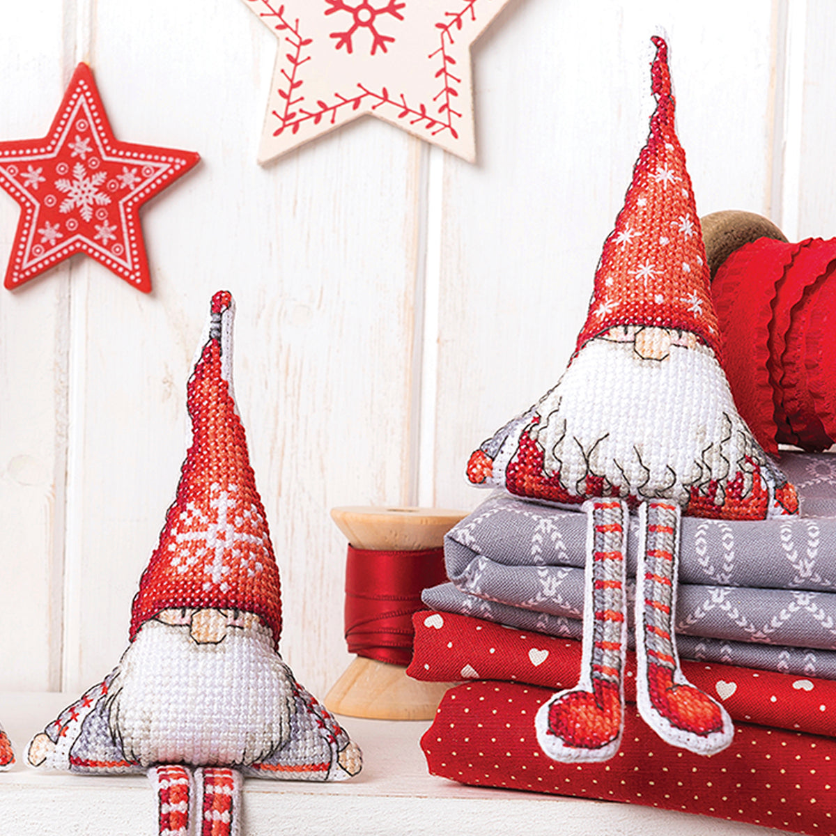 Two Christmas-themed gnomes with red hats and white beards on a wooden surface with decorative stars in the background.