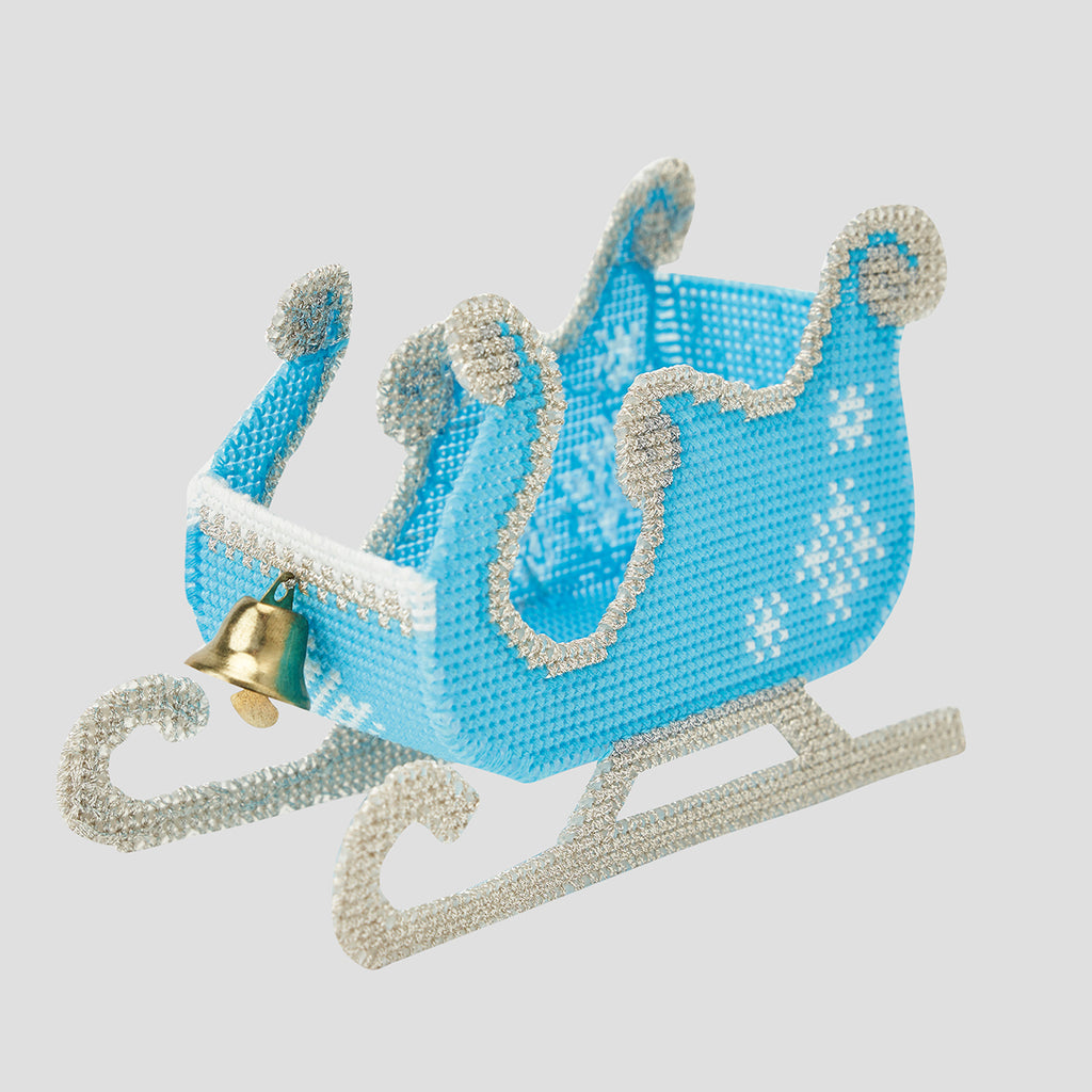 Decorative blue sleigh with silver trim and a gold bell on a light gray background