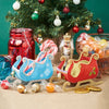 Decorative Christmas items including a blue sleigh, red sleigh, candy, and a nutcracker in front of a decorated tree.
