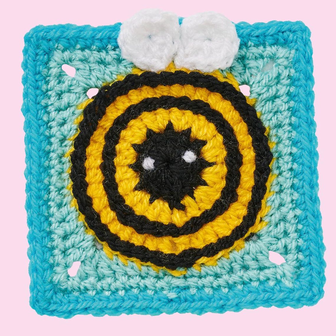 Crocheted bee motif with black, yellow circles, and white eyes on a turquoise square background, evoking a cheerful, playful vibe.