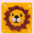 A crocheted square with a cute lion face in the center. The lion has a round yellow face, brown mane, black eyes, and a pink background. Playful and cheerful.