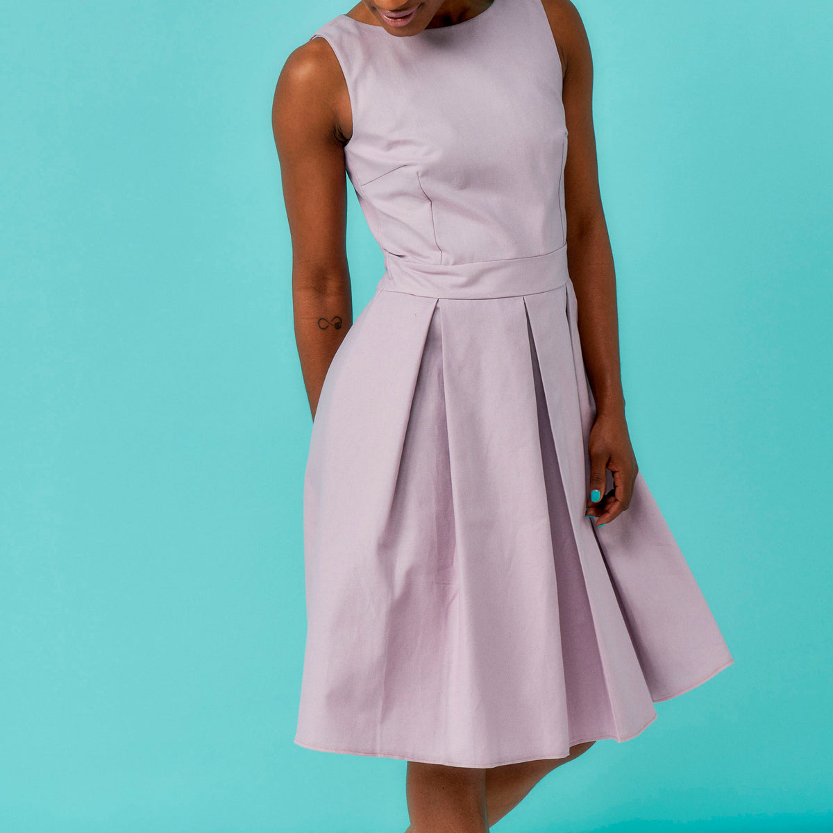 Light purple sleeveless dress worn by a person on a teal background