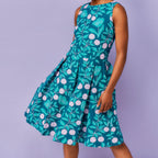 Woman wearing a sleeveless dress with a floral pattern on a purple background