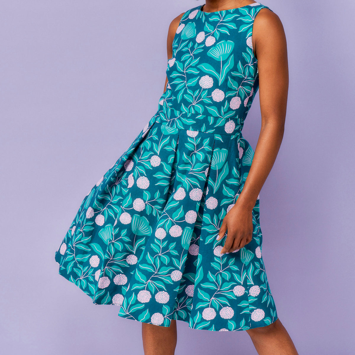 Woman wearing a sleeveless dress with a floral pattern on a purple background