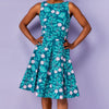 Woman wearing a teal dress with floral pattern against a purple background