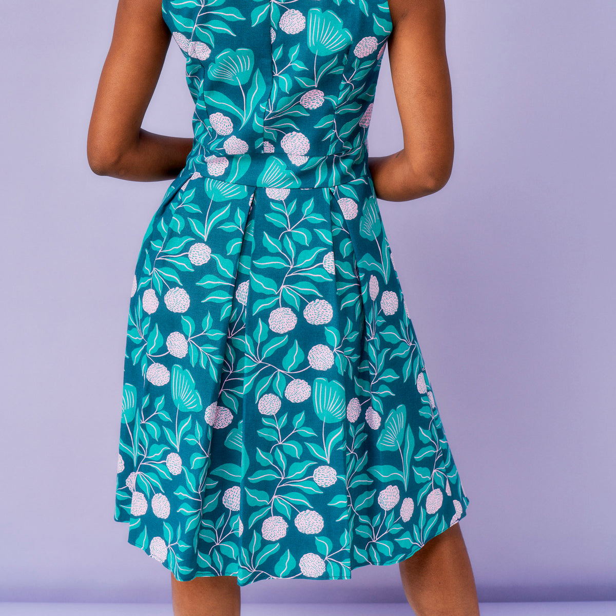 Green floral dress on a person against a purple background
