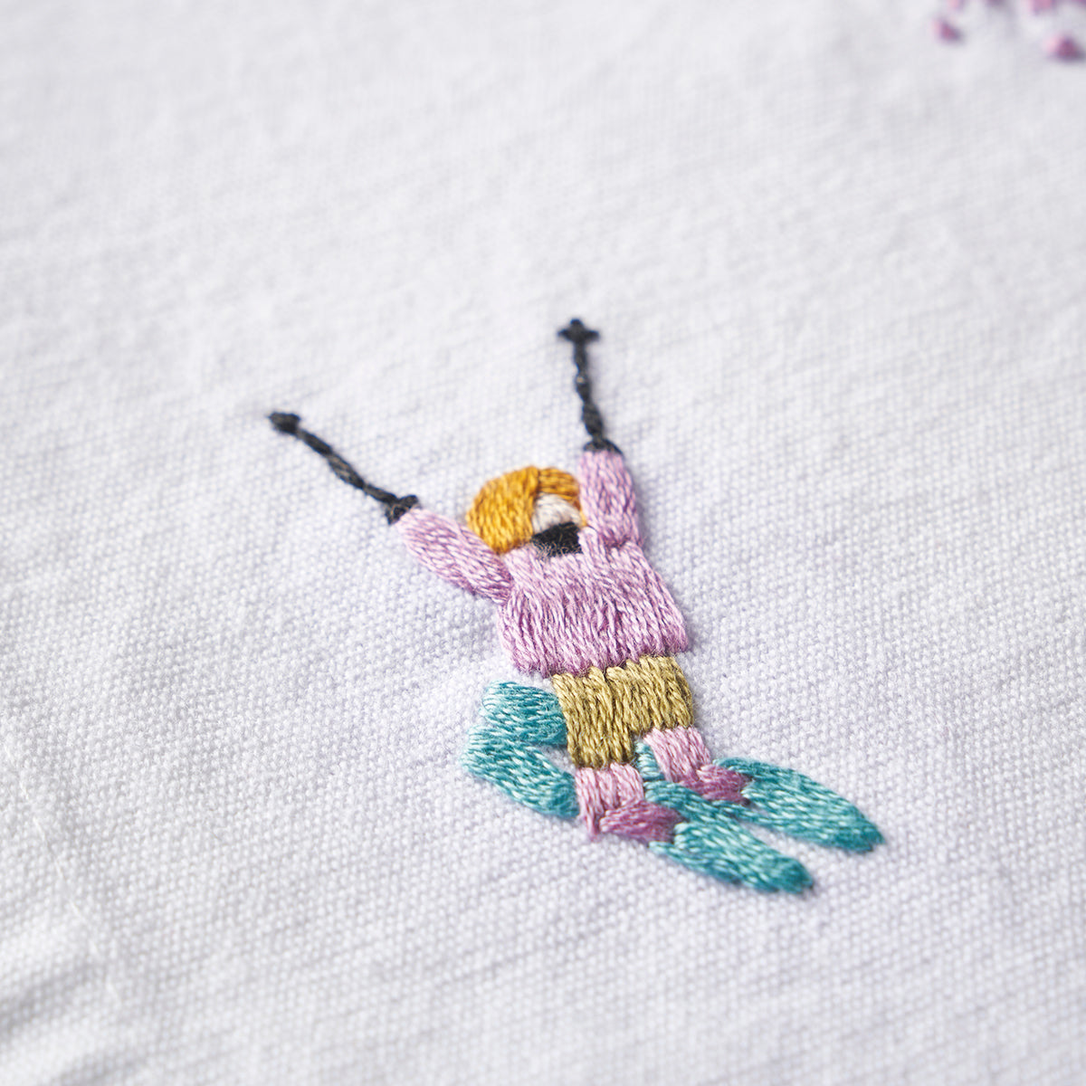 Embroidery of a person skiing on a white fabric background