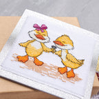 Cross-stitched design of two ducks on a white fabric background