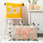 Two decorative pillows with 'JOY' and 'YAY' text on a white surface.