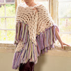 A person arm knitting a large, chunky, multicolored scarf made of wool.