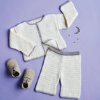 Knitted baby outfit with cardigan, pants, and shoes on a purple background