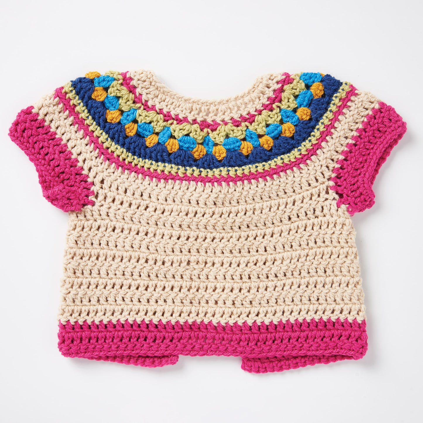 A handmade crocheted baby shirt with a multicolored yoke featuring blue, green, orange, and pink hues. The body is cream, and the sleeves and hem are pink.