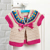 Crocheted baby cardigan with colorful yoke of blue, yellow, and green, pink sleeves and trim, tied with a pink ribbon on a blue hanger.