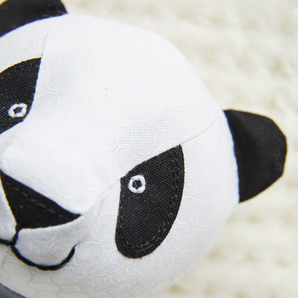 Close-up of a panda-shaped plush toy on a soft beige background