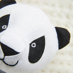 Close-up of a panda-shaped plush toy on a soft beige background