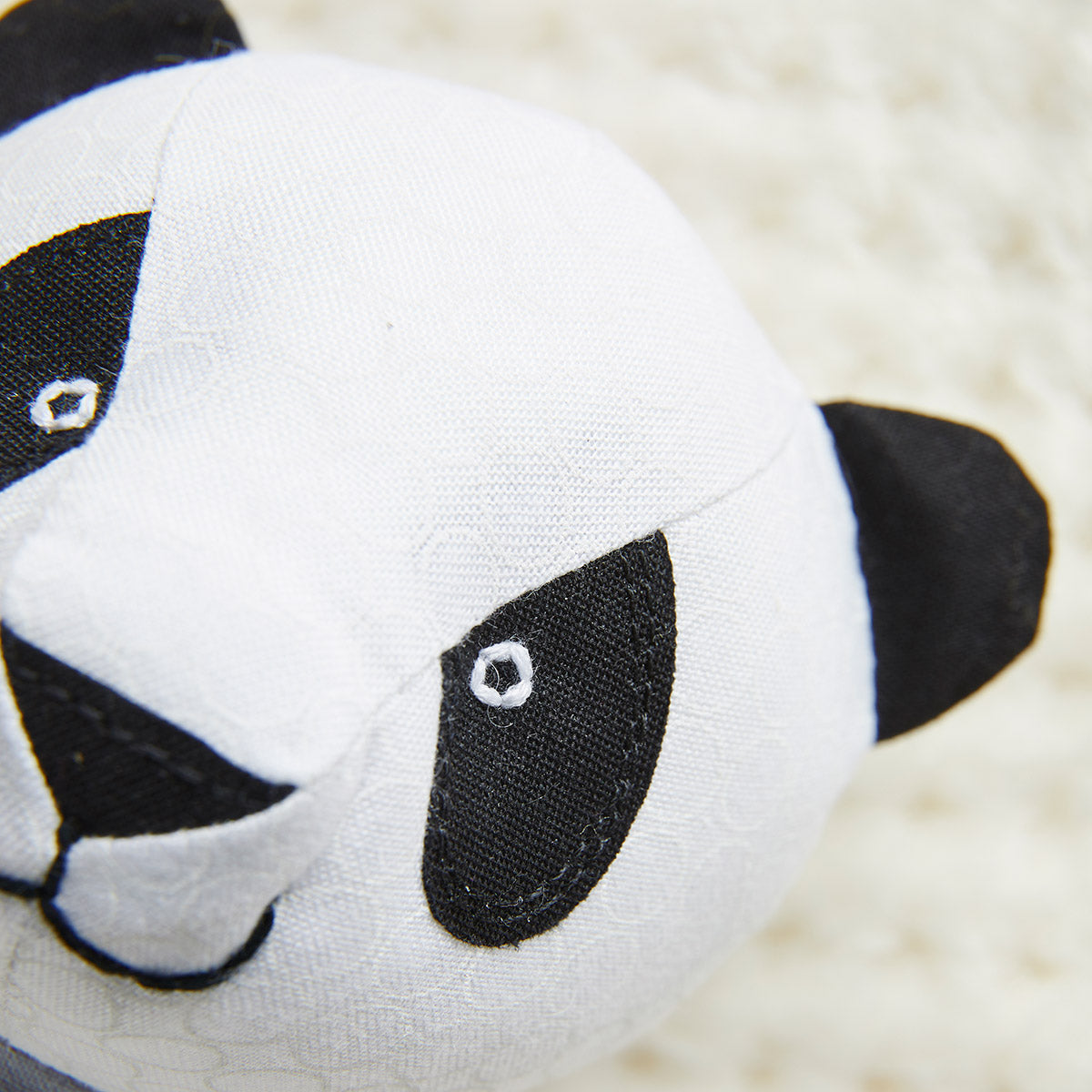 Close-up of a panda-shaped plush toy on a soft beige background