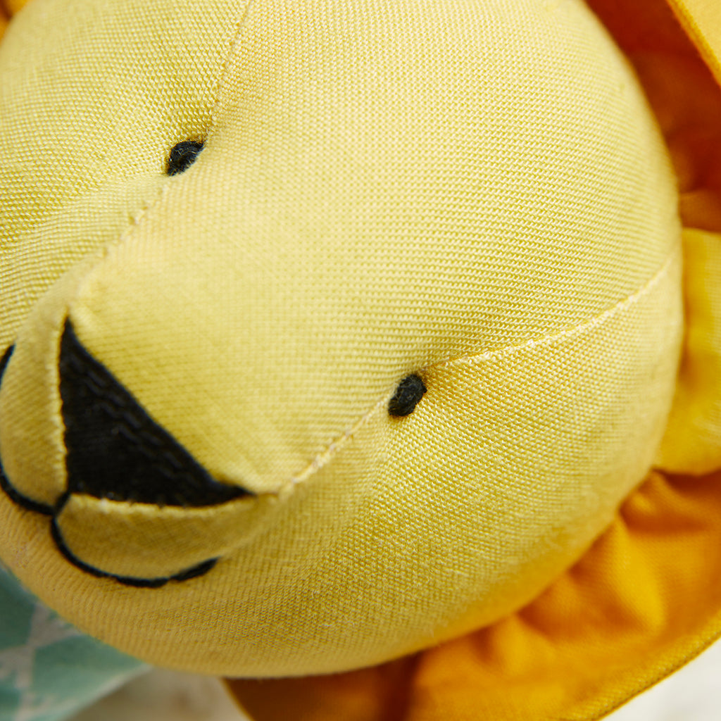 Close-up of a yellow plush toy with black details on a blurred background