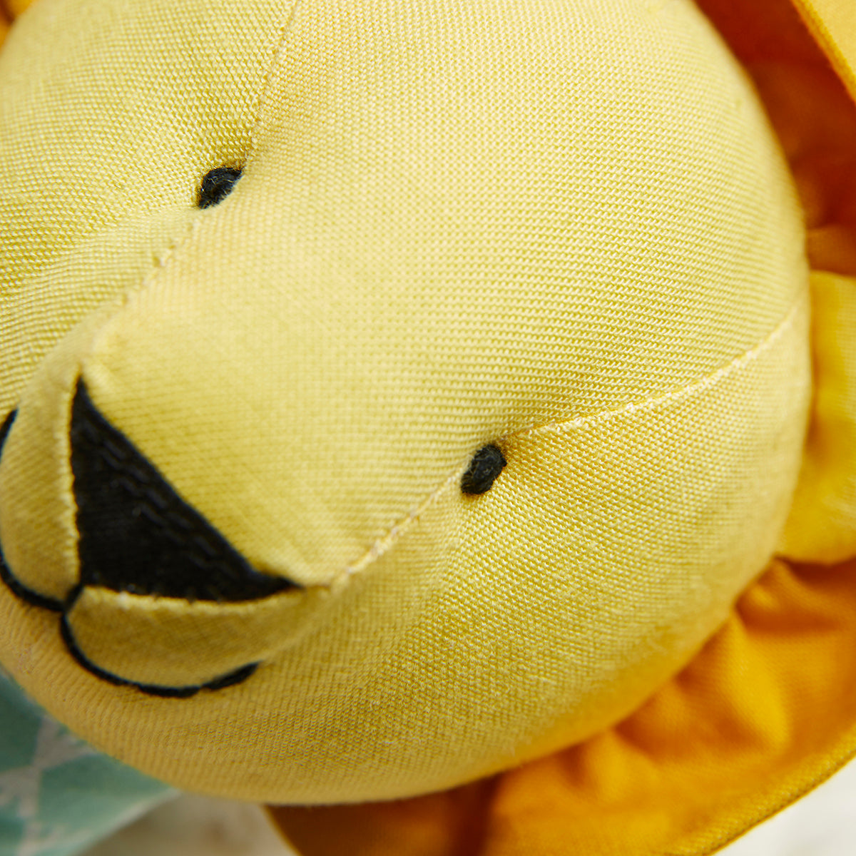 Close-up of a yellow plush toy with black details on a blurred background