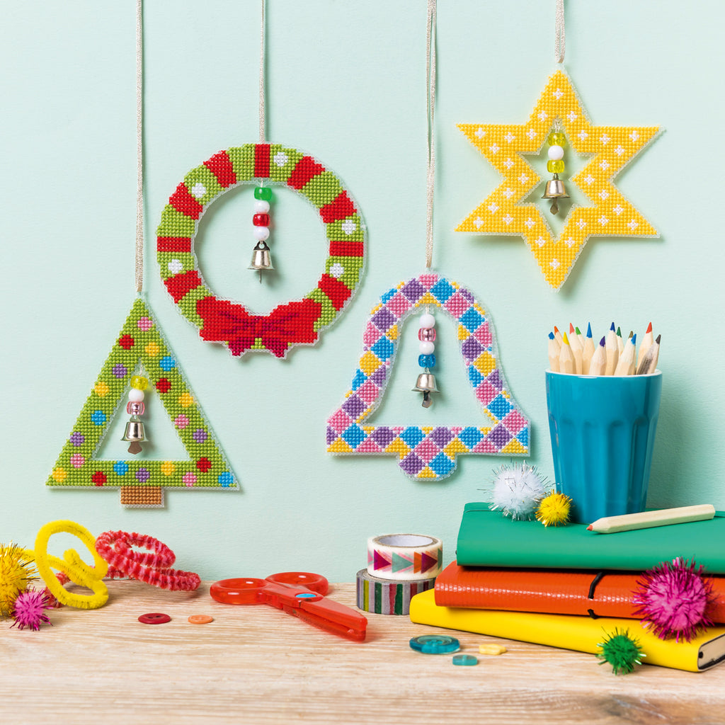 Colorful geometric decorations hanging on a light blue wall with stationery items on a wooden surface.