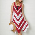 Woman wearing a red and white crocheted dress holding a hat against a white background