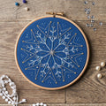 Embroidery hoop with blue fabric and star pattern on a wooden surface