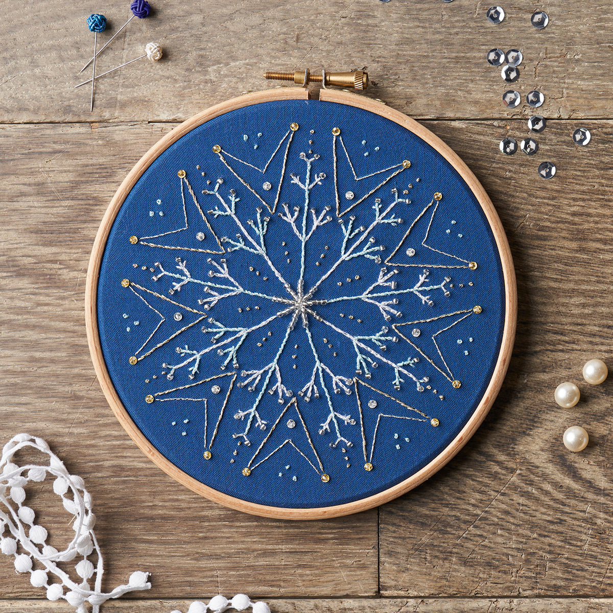 Embroidery hoop with blue fabric and star pattern on a wooden surface