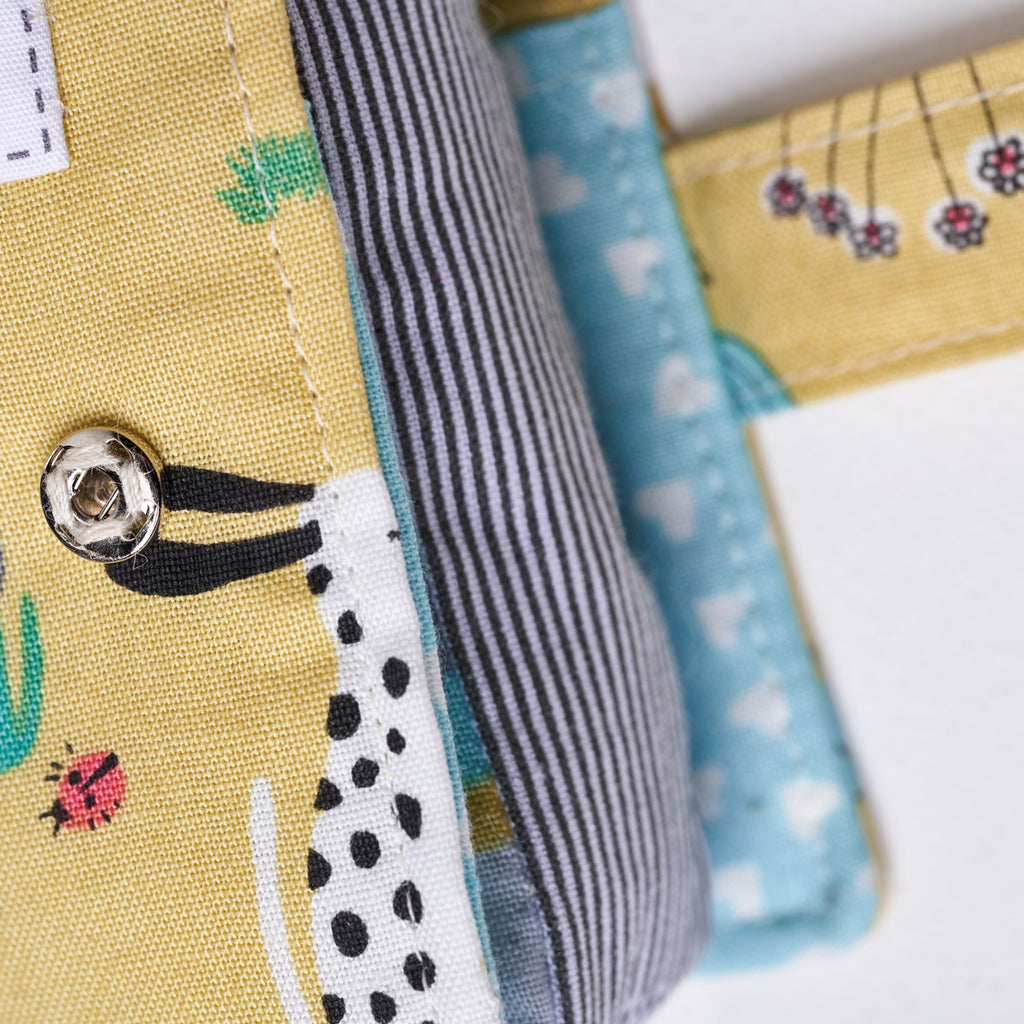 Close-up of fabric with various patterns and a button on a white background