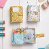 Set of colorful fabric sewing pouches with various sewing tools on a white wooden surface.