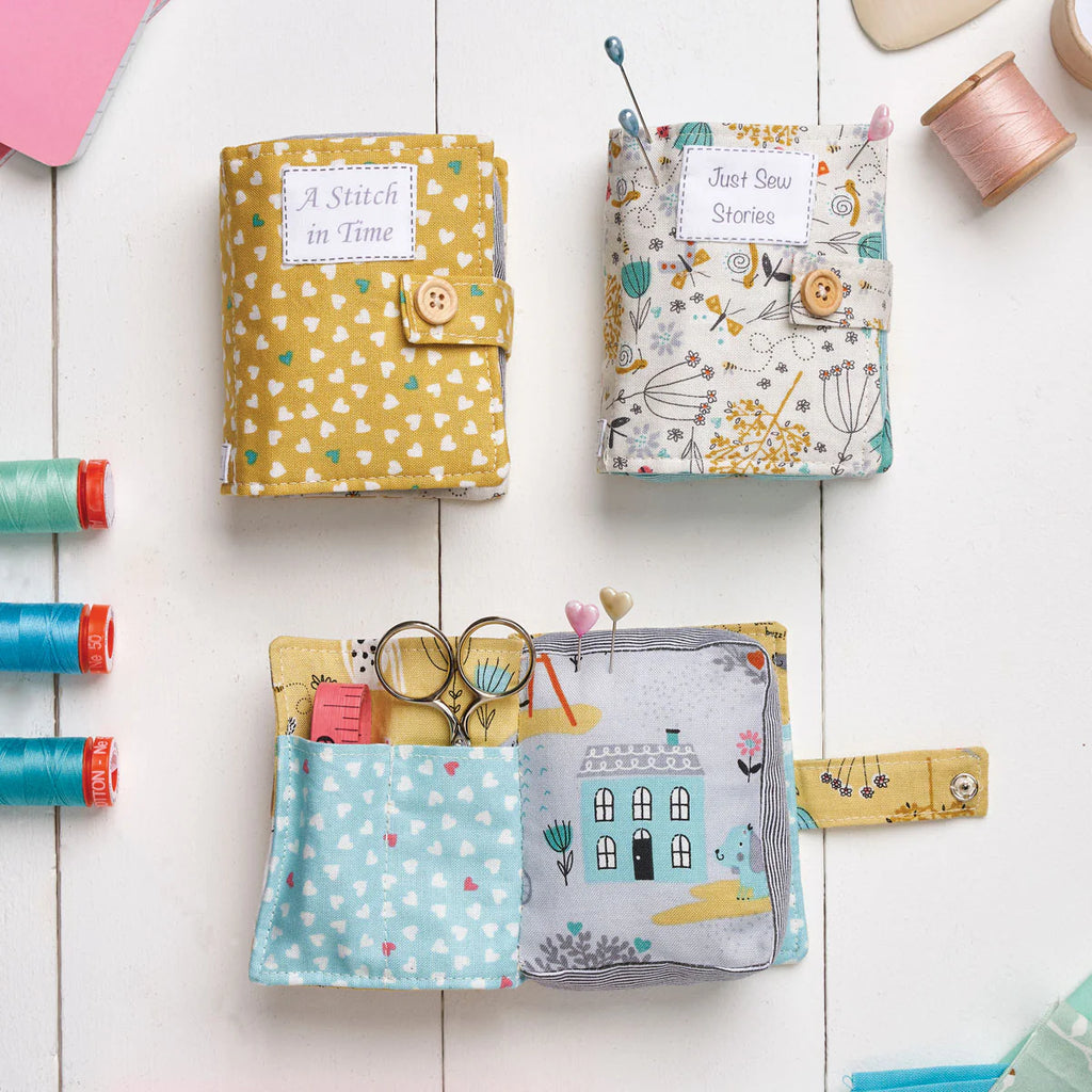 Set of colorful fabric sewing cases with various sewing tools on a white wooden surface