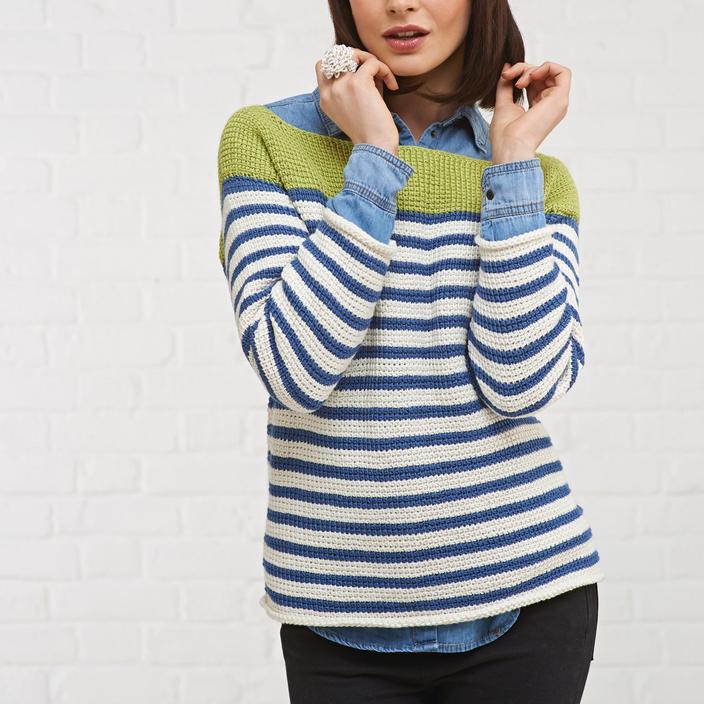 Woman wearing a striped sweater with green, blue, and white colors against a white background