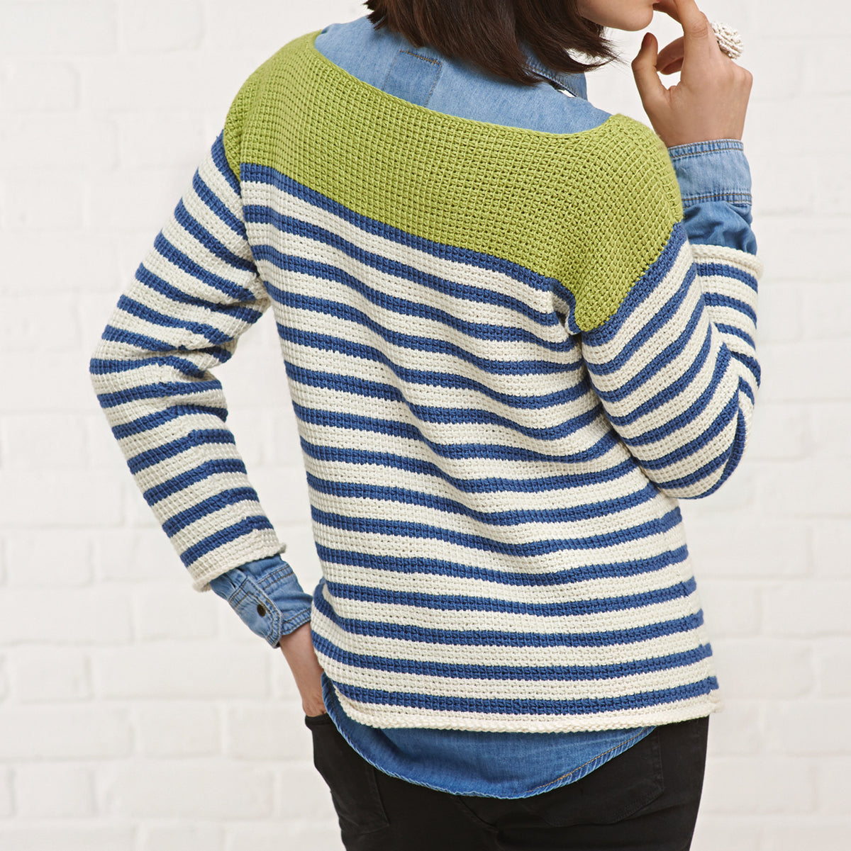 Person wearing a striped sweater with green and blue sections against a white background