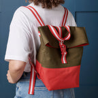 Person wearing a brown and red backpack against a blue background