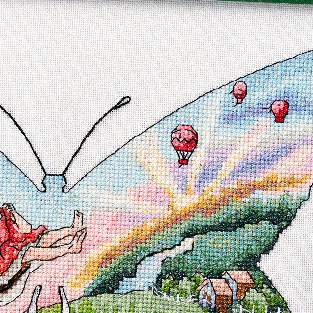 Cross-stitched butterfly with colorful wings and hot air balloons in the background
