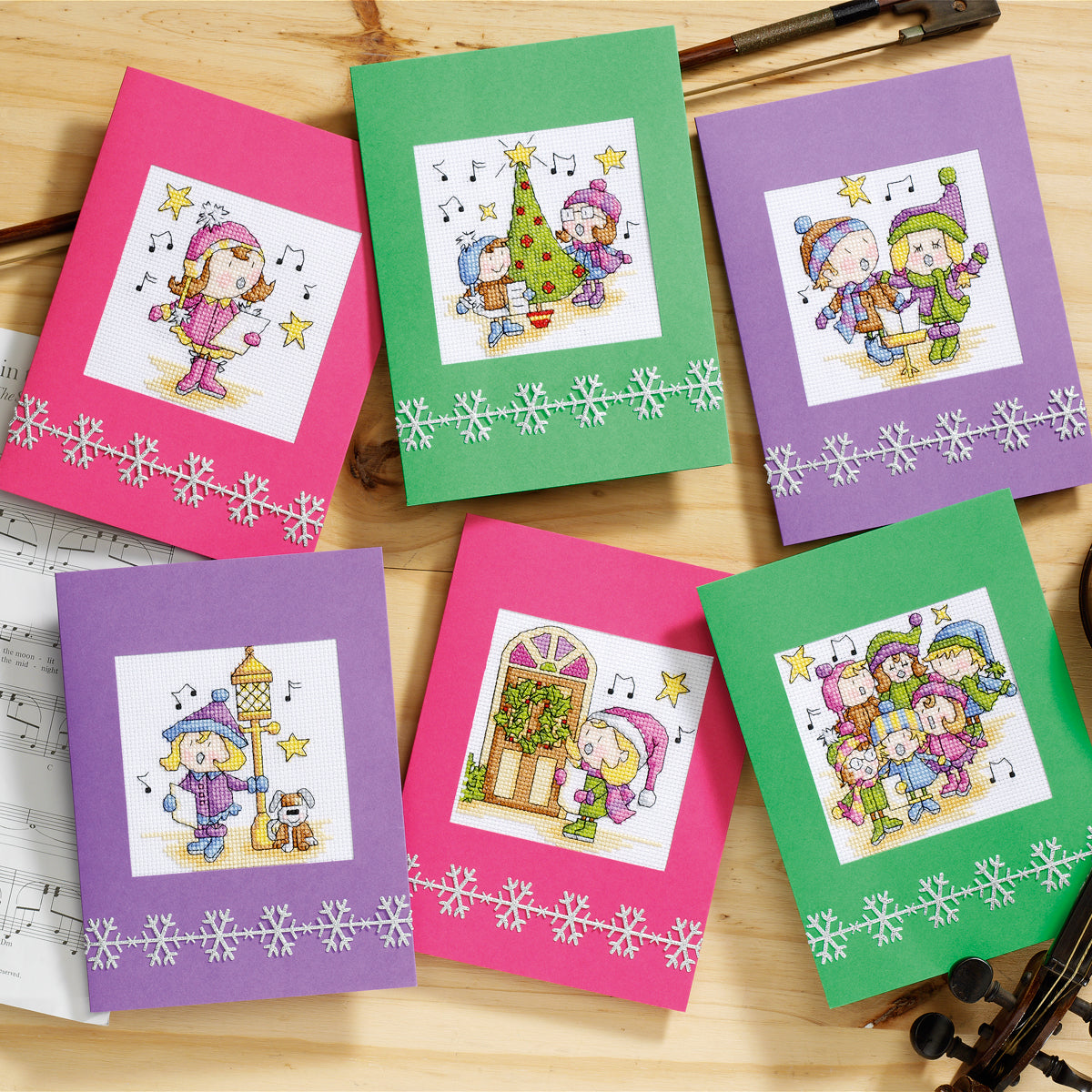 Set of colorful greeting cards with winter-themed illustrations on a wooden surface.