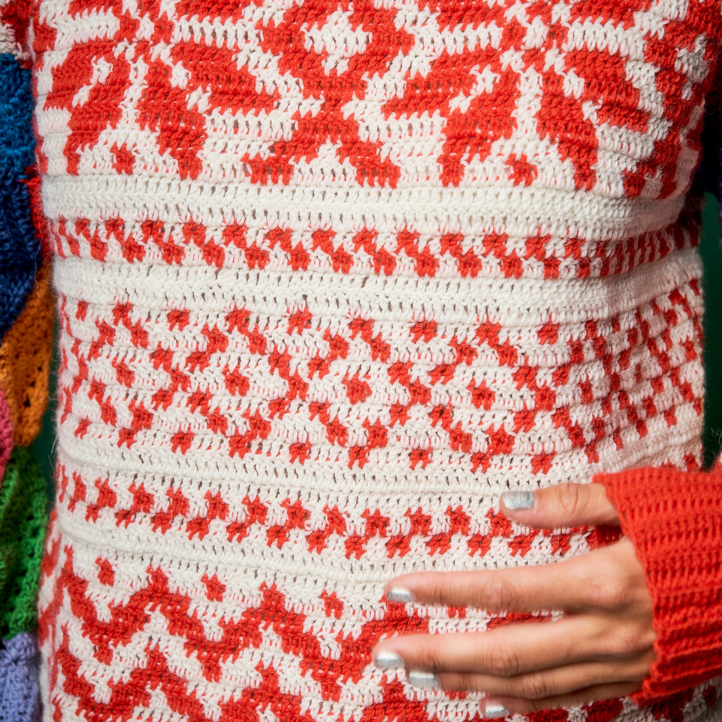 Close-up of a red and white patterned fabric with a hand holding it.