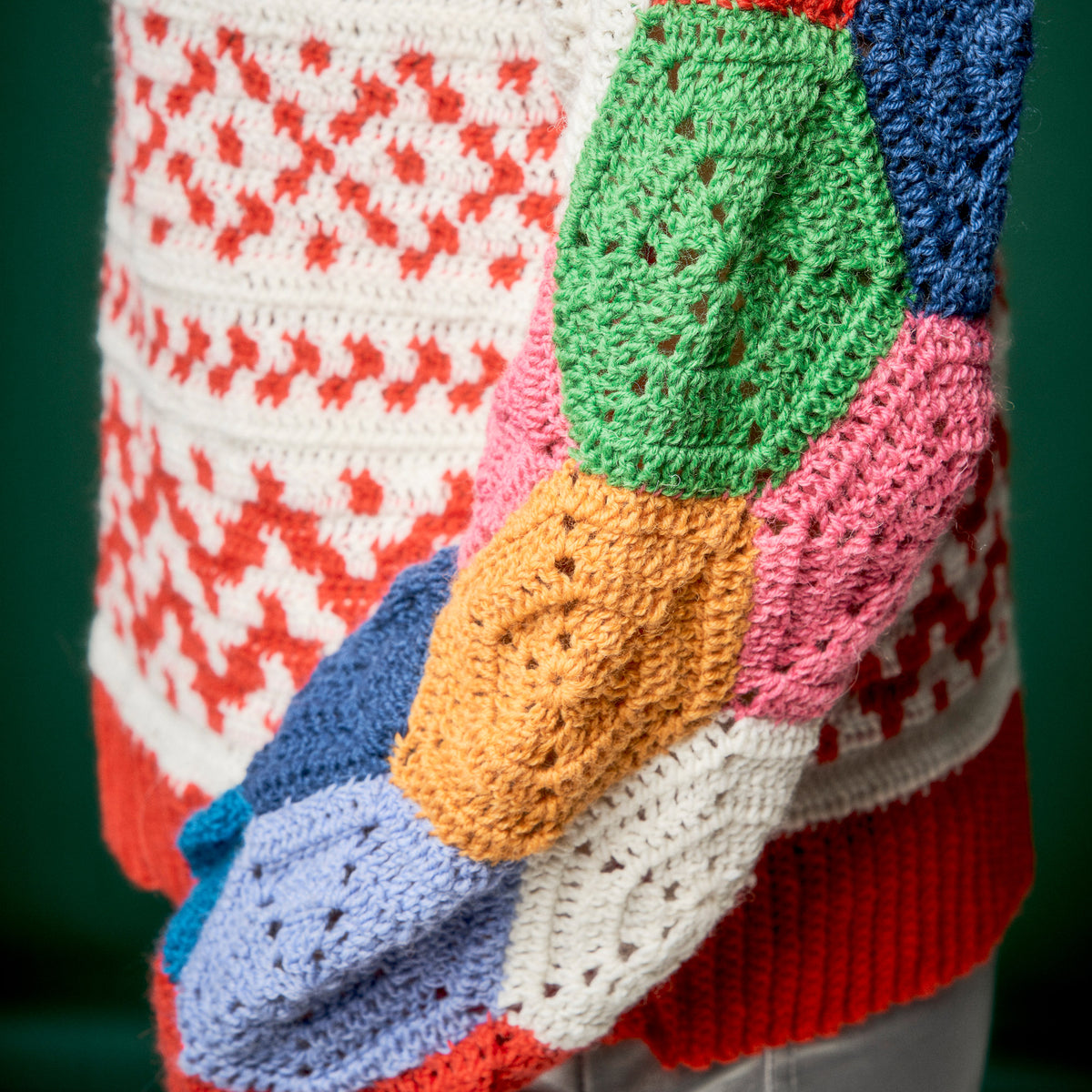 Colorful patchwork crochet blanket with geometric patterns on a dark background