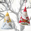 Two cross stitch Christmas ornaments, one of an angel and one of Santa Claus, against a snowy branch background.