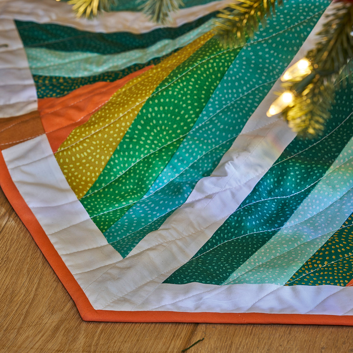 Quilt with green and orange patterns on a wooden surface